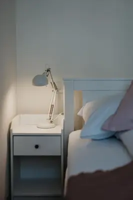 a lamp on a night stand next to a bed at Sight Main Square & Main Train Station & Planty in Kraków