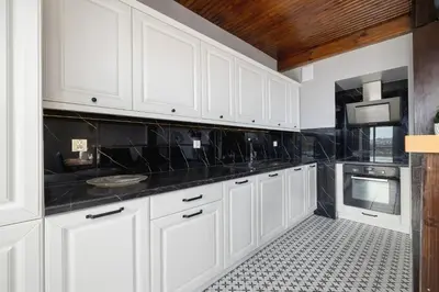 a kitchen with white cabinets and black counter tops at Apartment with terrace - Skawińska 20 in Kraków