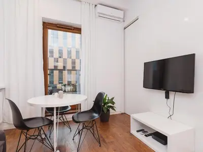 a living room with a table and chairs and a tv at Apartment with balcony - Pawia 34 Street in Kraków