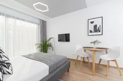 a white bedroom with a bed and a table and chairs at Apartment for two - Piłsudskiego 1 Street in Kraków
