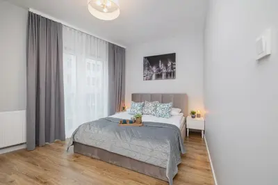 a white bedroom with a bed and a window at Kiełkowskiego Modern & Comfy Apartment with Balcony Cracow by Noclegi Renters in Kraków