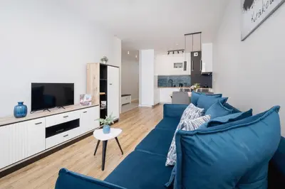 a living room with a blue couch and a tv at Kiełkowskiego Modern & Comfy Apartment with Balcony Cracow by Noclegi Renters in Kraków