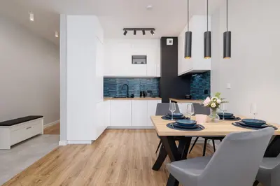 a kitchen and dining room with a wooden table and chairs at Kiełkowskiego Modern & Comfy Apartment with Balcony Cracow by Noclegi Renters in Kraków