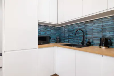 a kitchen with white cabinets and a sink at Kiełkowskiego Modern & Comfy Apartment with Balcony Cracow by Noclegi Renters in Kraków