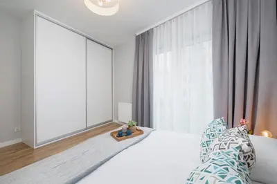 a bedroom with a white bed and a large window at Kiełkowskiego Modern & Comfy Apartment with Balcony Cracow by Noclegi Renters in Kraków