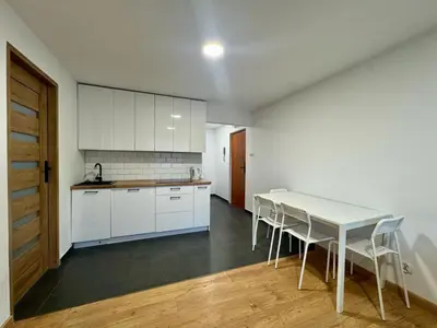 a kitchen with white cabinets and a table and chairs at Apartament Bałandy 26 in Oświęcim