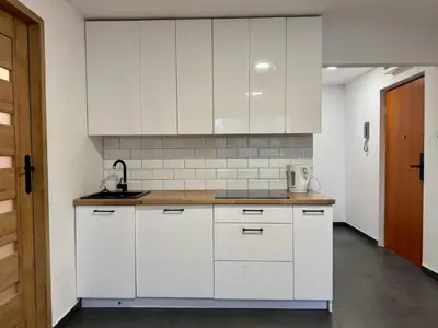 a kitchen with white cabinets and a sink at Apartament Bałandy 26 in Oświęcim