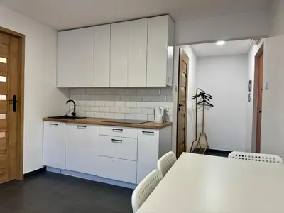 a kitchen with white cabinets and a table and chairs at Apartament Bałandy 26 in Oświęcim
