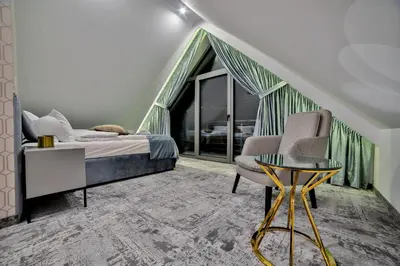 a bedroom with a bed and a chair and a table at Kompleks Gazdówka - Dom Jana in Ponice