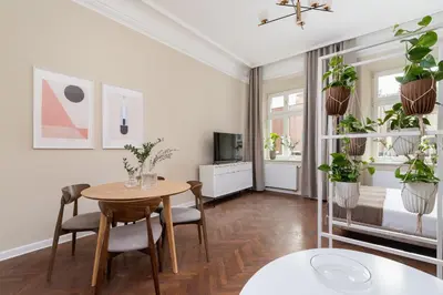 a living room with a table and chairs and potted plants at 3-Bedroom Apartment - Rejtana 10 in Kraków