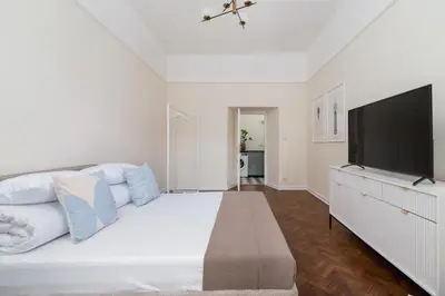a white bedroom with a large bed and a flat screen tv at 3-Bedroom Apartment - Rejtana 10 in Kraków