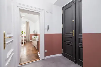 a hallway with a black door and a living room at 2-Bedroom Apartment - Rejtana 10 in Kraków