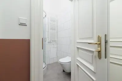 a white bathroom with a toilet and a glass door at 2-Bedroom Apartment - Rejtana 10 in Kraków