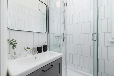a white bathroom with a sink and a shower at 2-Bedroom Apartment - Rejtana 10 in Kraków