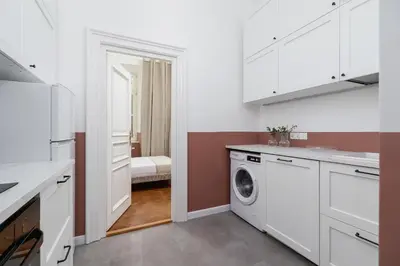 a kitchen with white cabinets and a washer and dryer at 2-Bedroom Apartment - Rejtana 10 in Kraków