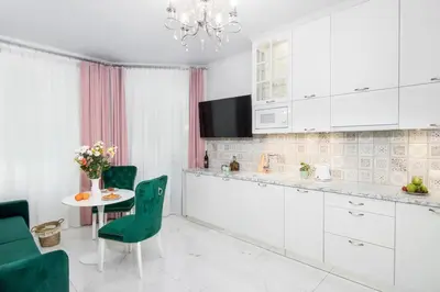 a kitchen with white cabinets and a table with green chairs at 1 - bedroom Apartment - Plac na Groblach 19 in Kraków