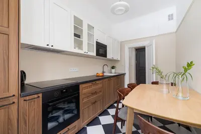 a kitchen with white cabinets and a wooden table at 2 - bedroom Apartment - Rejtana 10 in Kraków