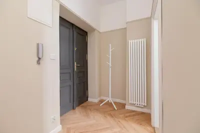 a hallway with a black door and wooden floors at 2 - bedroom Apartment - Rejtana 10 in Kraków