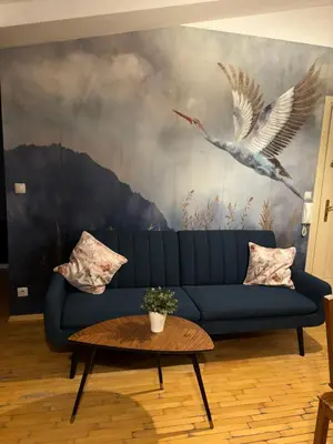 a living room with a blue couch and two birds at Blue Moon Main Square Apartment in Kraków