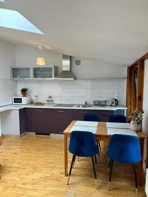a kitchen with a wooden table and blue chairs at Blue Moon Main Square Apartment in Kraków