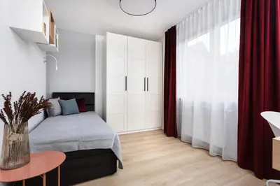 a bedroom with a bed and a table and a window at SOL Apartment in Kraków