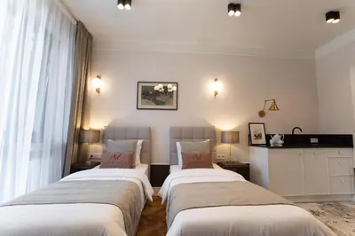 two beds in a room with white walls at Avanti Villa in Kraków