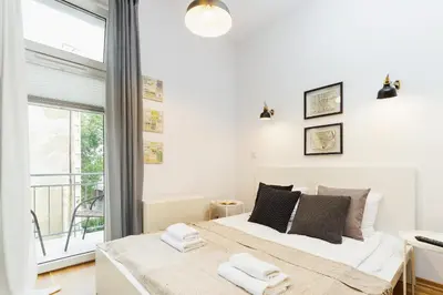 a white bedroom with a bed and a balcony at Apartment with balcony - Rzeszowska 4 Street in Kraków