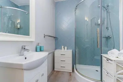 a white bathroom with a shower and a sink at Apartment with balcony - Rzeszowska 4 Street in Kraków