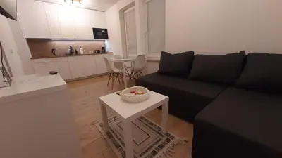 a living room with a black couch and a table at Apartamenty Kraków-Bielany in Kraków
