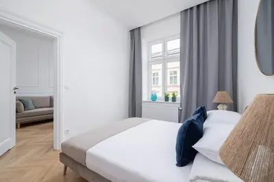 a white bedroom with a bed and a window at 4-Bedroom Apartment - Private Sauna - Wielopole 7 in Kraków