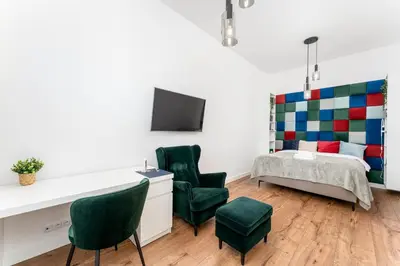 a bedroom with a bed and two green chairs at Józefińska Deluxe Studio by BookingHost in Kraków