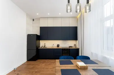 a kitchen with black cabinets and blue chairs and a table at Józefińska Deluxe Studio by BookingHost in Kraków