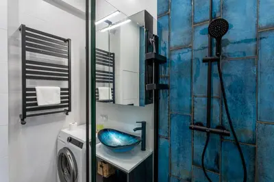 a bathroom with a shower and a blue sink at Józefińska Deluxe Studio by BookingHost in Kraków