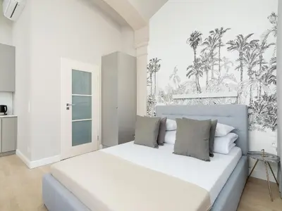 a white bedroom with a large bed with palm trees on the wall at Apartment - Main Square in Kraków