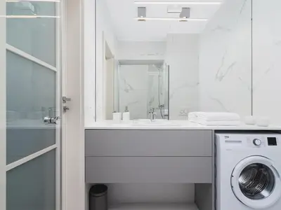 a white bathroom with a washing machine under a sink at Apartment - Main Square in Kraków