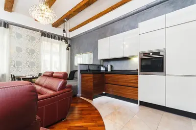 a kitchen with white cabinets and a red couch at Luxury Apartment - Kazimierz District in Kraków