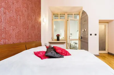 a bedroom with a white bed with two red pillows at Luxury Apartment - Kazimierz District in Kraków