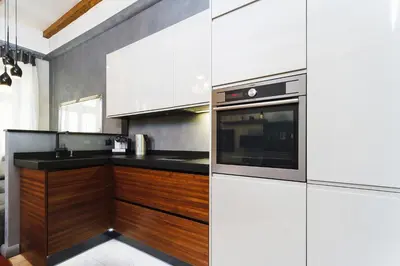 a kitchen with white cabinets and a black counter top at Luxury Apartment - Kazimierz District in Kraków