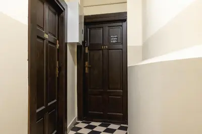 a wooden door in a hallway with a checkered floor at Zyblikiewicza 5- Studio Apartment- Old Town in Kraków