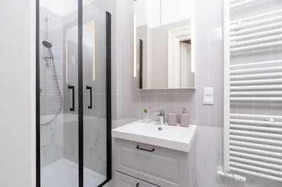 a white bathroom with a sink and a shower at Apartment with balcony - Rejtana 10 in Kraków