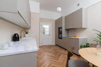 a kitchen with white cabinets and a wooden table at Apartment with balcony - Rejtana 10 in Kraków