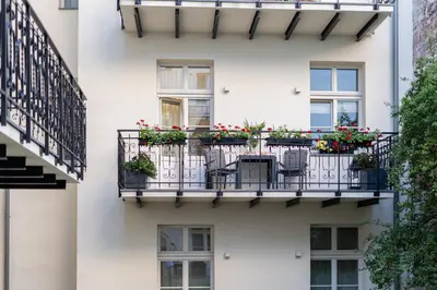 a white building with a balcony with flowers on it at Apartament w sercu Krakowa in Kraków
