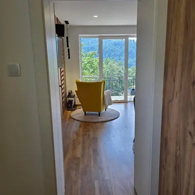 a yellow chair in a living room with a window at Mieszkanie nad Jeziorem Rożnowskim in Rożnów