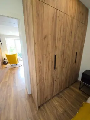 a large wooden door in a room with a yellow chair at Mieszkanie nad Jeziorem Rożnowskim in Rożnów