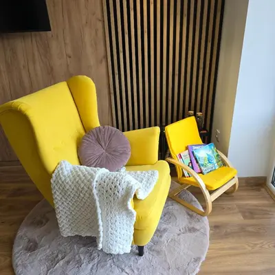 a yellow chair with a pillow and a table at Mieszkanie nad Jeziorem Rożnowskim in Rożnów