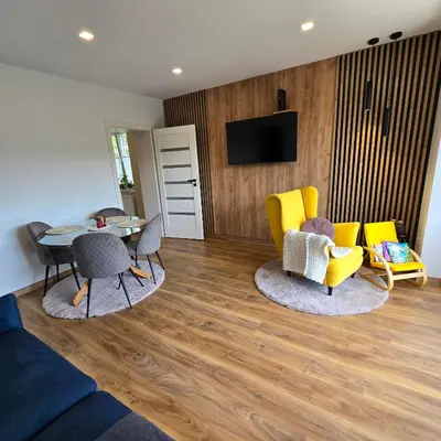 a living room with yellow chairs and a table at Mieszkanie nad Jeziorem Rożnowskim in Rożnów