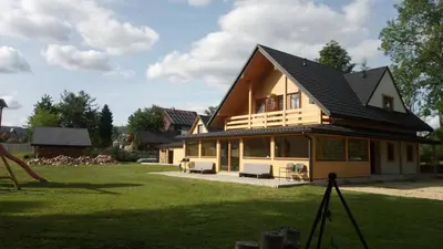 a house with a black roof on a yard at Dom Pod Wierzbami in Sidzina