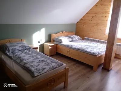 two beds in a room with wooden floors at Dom Pod Wierzbami in Sidzina