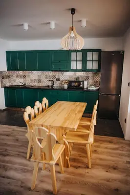 a kitchen with green cabinets and a wooden table and chairs at Dom Pod Wierzbami in Sidzina