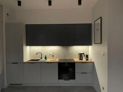a kitchen with white counters and black cabinets at Quantum Premium Apartment & Free Parking! in Kraków